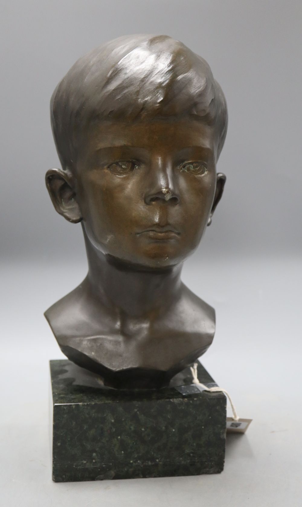 A bronze bust of a boy, signed R.Swann 1930, on marble base, height 38cm, some scuffing to the nose shows some white metal although we
